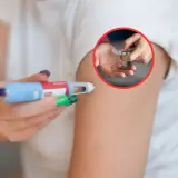 Dłoń z pisakiem do iniekcji i blister z tabletkami w kółku.